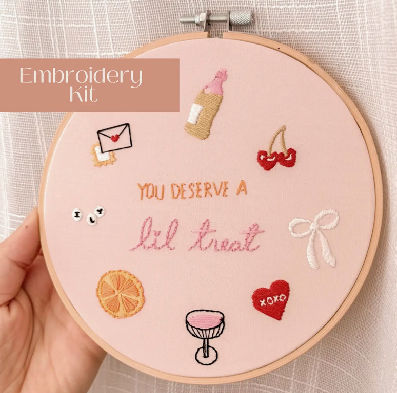 Embroidery hoop with completed embroidery design featuring various elements and text.