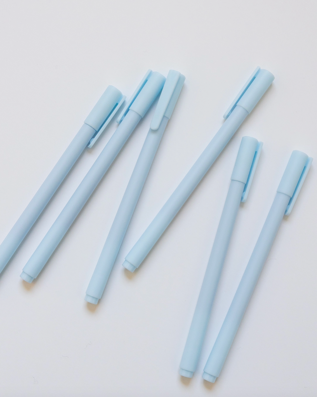 Set of light blue pens on a white background