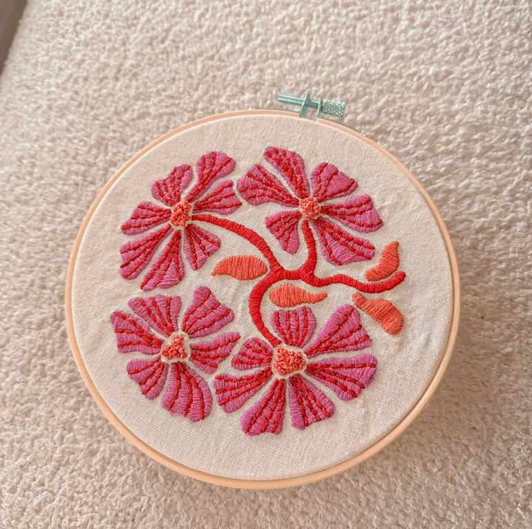 Embroidery hoop with pink floral design on a beige background