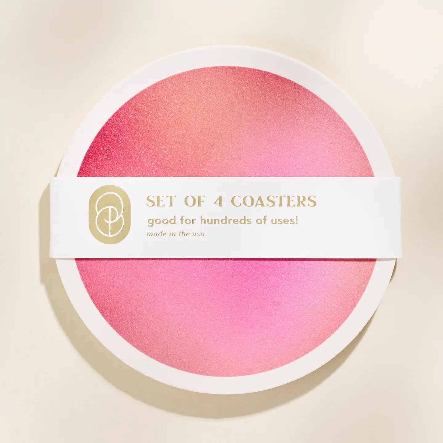 Set of 4 pink coasters in packaging with a visible brand logo on a beige background