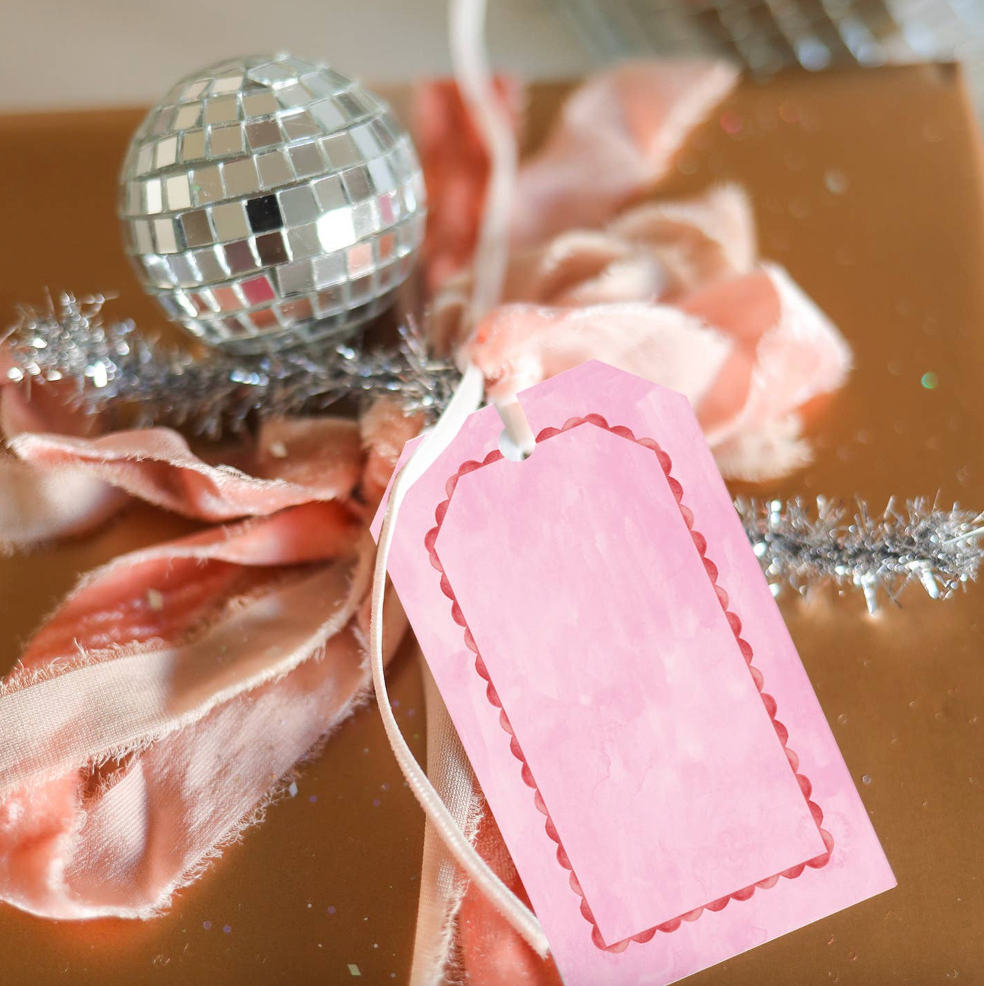 Decorative setup with pink flowers, a disco ball, and a pink tag on a reflective surface.