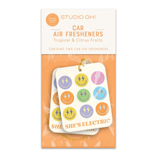 "Drive in Style" – Close-up of the “She Is Electric” freshie hanging from a rearview mirror

"Cute Car, Fresh Vibes" – Two-pack of fresheners styled with keys and a colorful dashboard

"Smells Like Girl Power" – Flatlay of freshener packaging next to lip balm and sunglasses