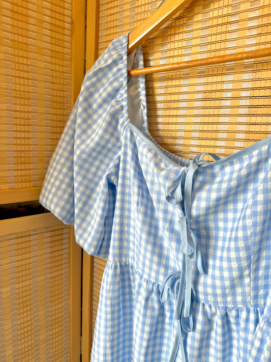 Sleeveless gingham dress with fitted bodice and flowy skirt.