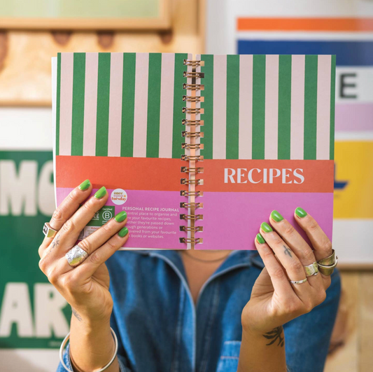 Person holding a spiral-bound recipe book with colorful cover