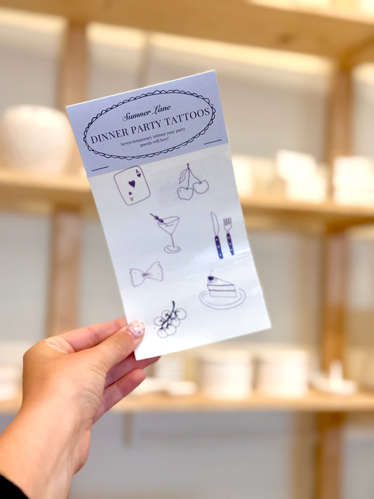 Sheet of dinner party tattoos held by a hand with a blurred background