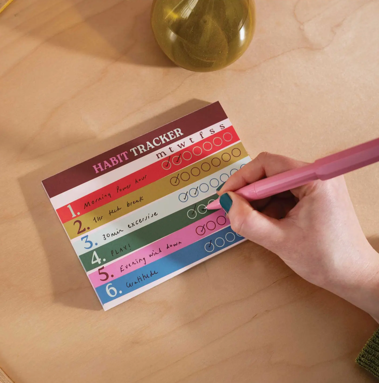 Habit tracker with colorful checkboxes on a wooden surface