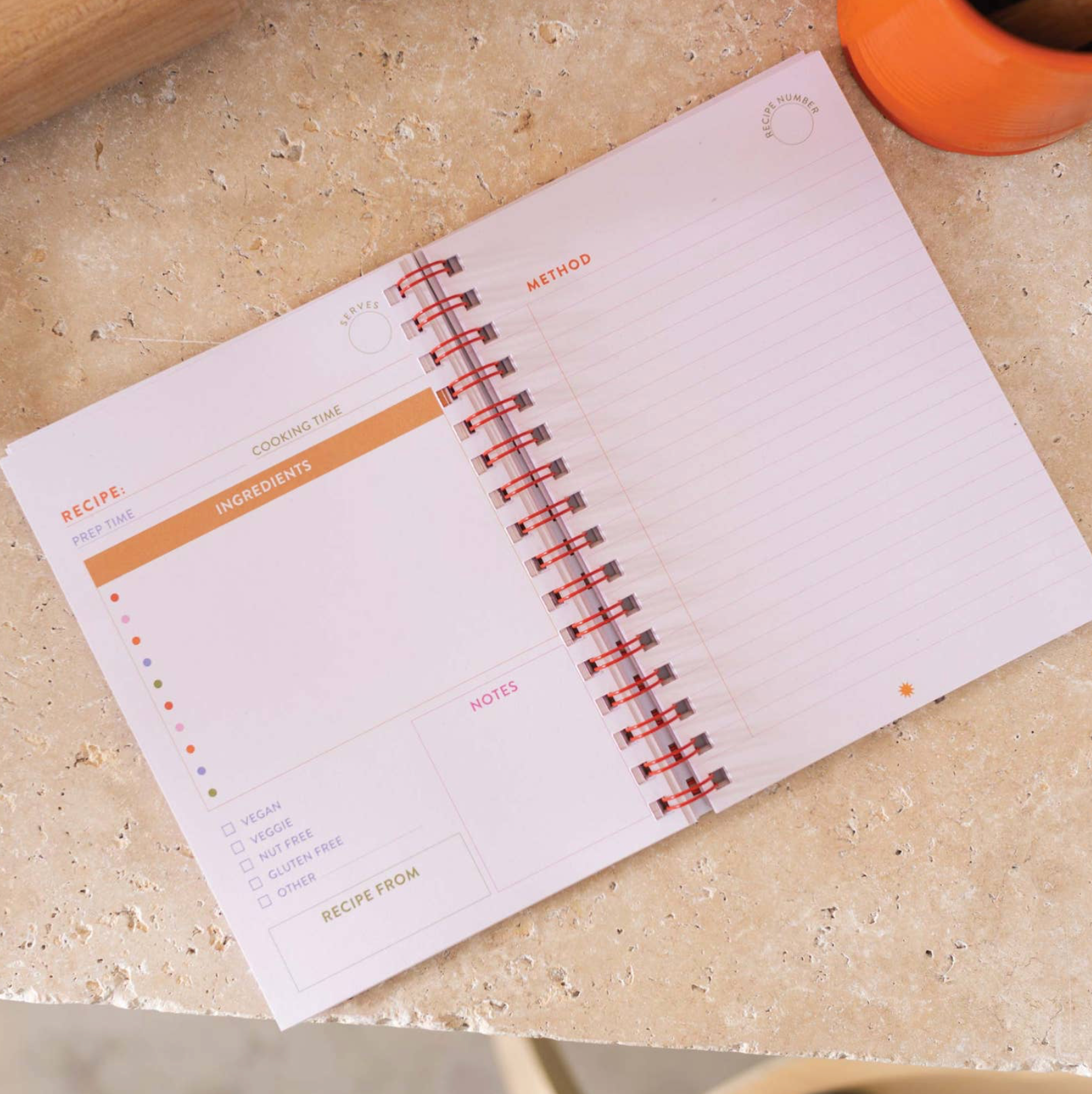 Open spiral-bound notebook on a beige surface with visible pages.
