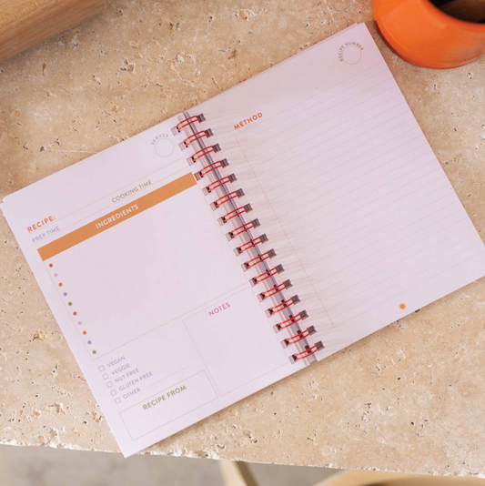 Open spiral-bound notebook on a beige surface with visible pages.