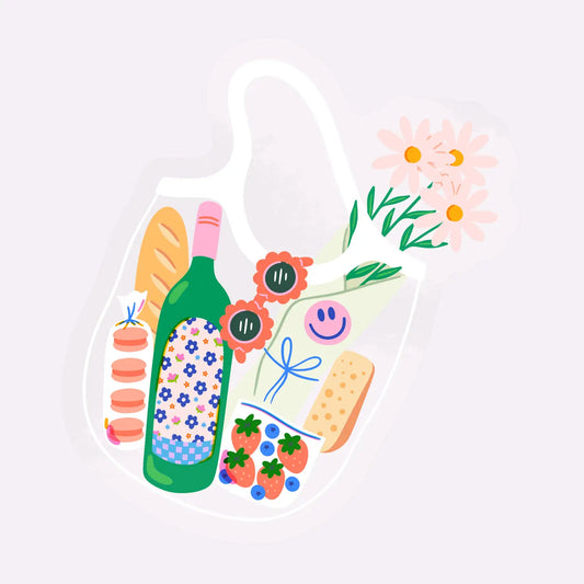 “Picnic Dreams” – Clear sticker on a water bottle with picnic blanket and strawberries in the background

“Market Mornings” – Sticker on a laptop with a woven basket, fresh flowers, and sunlight

“Cottagecore Chic” – Sticker on a journal, surrounded by spring florals and a pastry