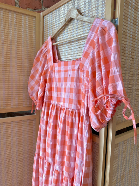 Pink gingham dress with adjustable sleeve ties.