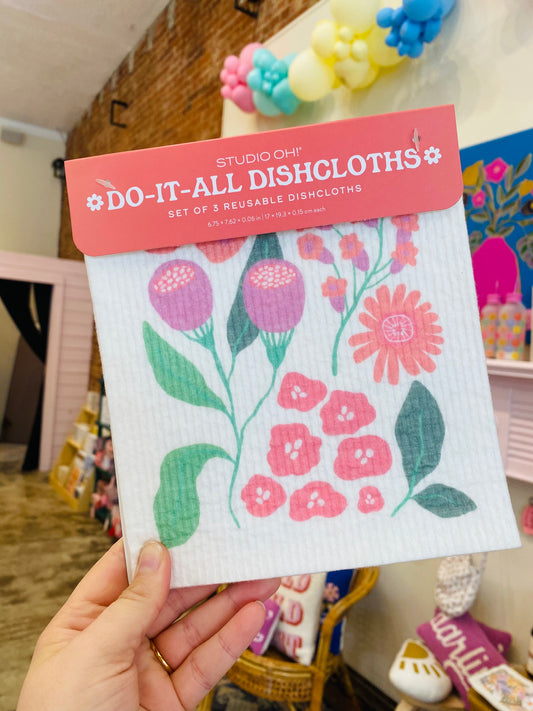 "Floral & Functional" – Three folded floral dishcloths with a pastel cleaning caddy

"Bloom While You Clean" – Dishcloth in use on a countertop next to a vase of fresh flowers

"Eco-Clean Dream Team" – Set of cloths laid out beside natural cleaning supplies and a sunny sink