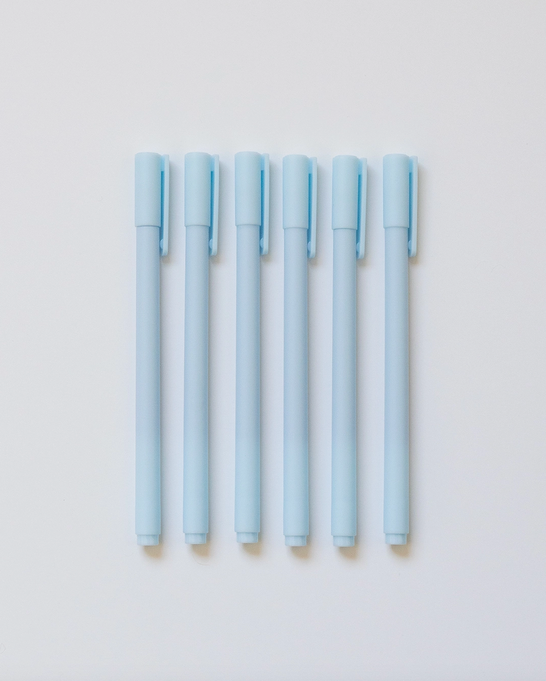 Set of light blue pens on a light gray background