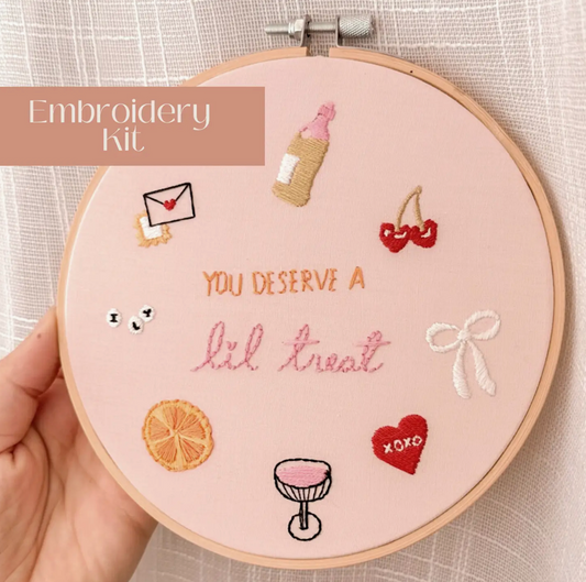 Embroidery hoop with completed embroidery design featuring various elements and text.