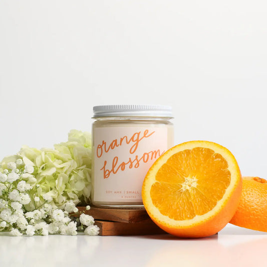 “Orange Blossom Glow” – Hand-poured candle styled beside fresh citrus and flowers

“Citrus Dream Candle” – Close-up of lit soy candle in a cozy, sunlit setting