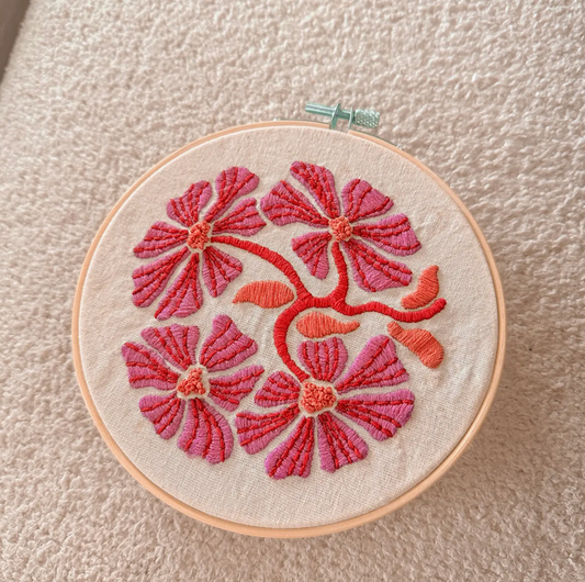Embroidery hoop with pink floral design on a beige background
