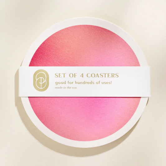 Set of 4 pink coasters in packaging with a visible brand logo on a beige background