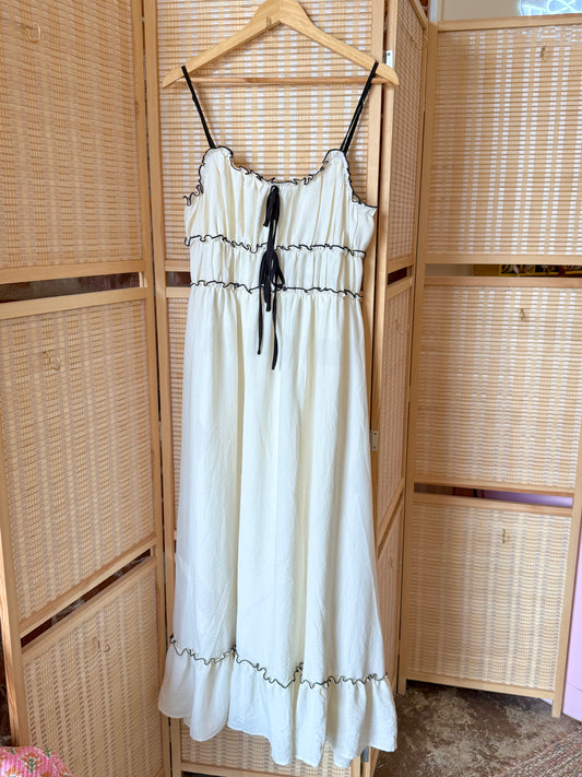 Soft woven cotton dress with contrast stitching and bow detail.