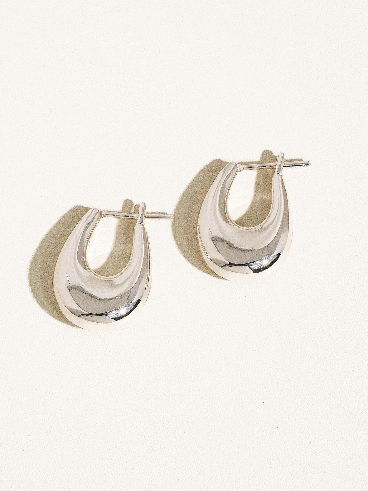 “Silver Droplet Hoop Earrings” – Elegant earrings on soft grey velvet with natural light

“18K Silver Hoops Minimal Style” – Close-up of earring worn with a neutral outfit