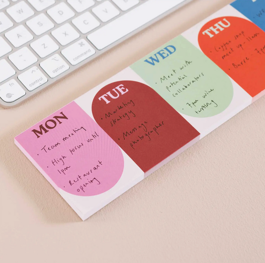 Colorful weekly planner sticky notes on a desk with a keyboard